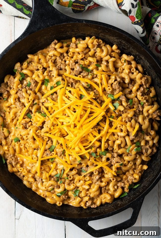 Top-down view of a cast iron skillet brimming with freshly made homemade hamburger helper, showcasing its rich, creamy texture.