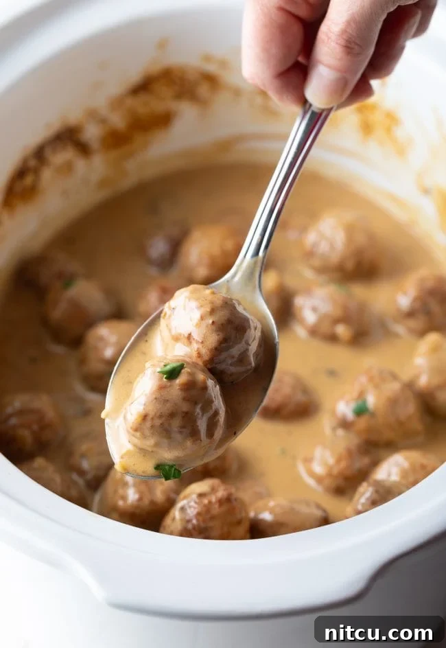 Creamy Swedish Meatballs cooked in a slow cooker, ready to serve over mashed potatoes.