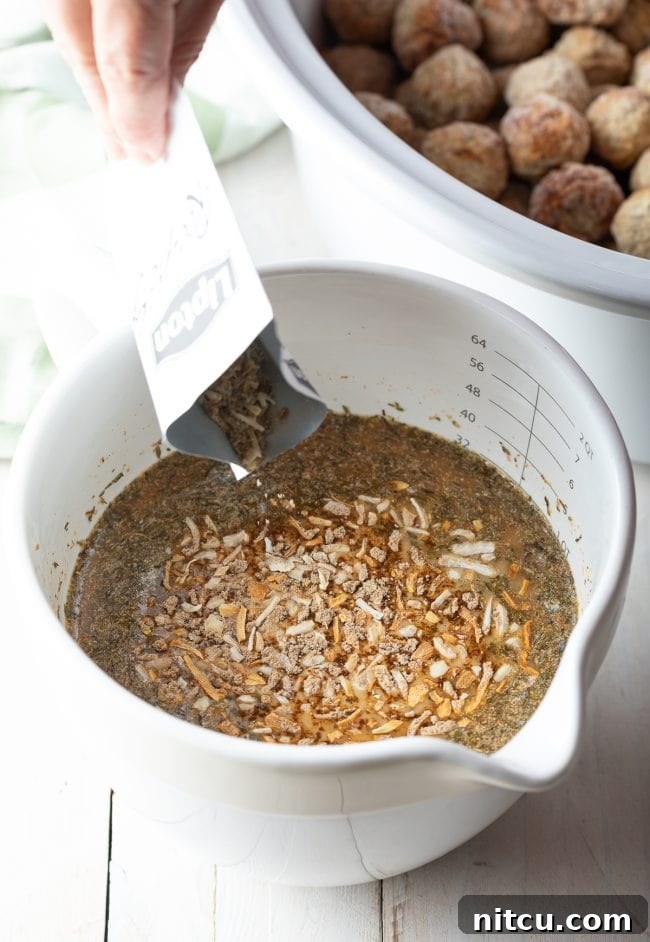 Close-up of a whisk mixing the creamy sauce ingredients in a bowl for the Swedish Meatballs.