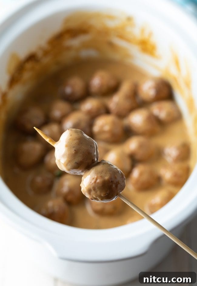 Cocktail party meatballs on a wooden party pick, ready to be served as an easy appetizer.