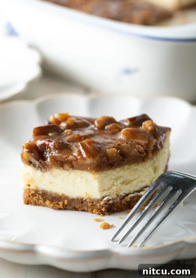 A pecan pie cheesecake bar on a plate with a fork, showing a bite removed to highlight the creamy texture and rich topping.