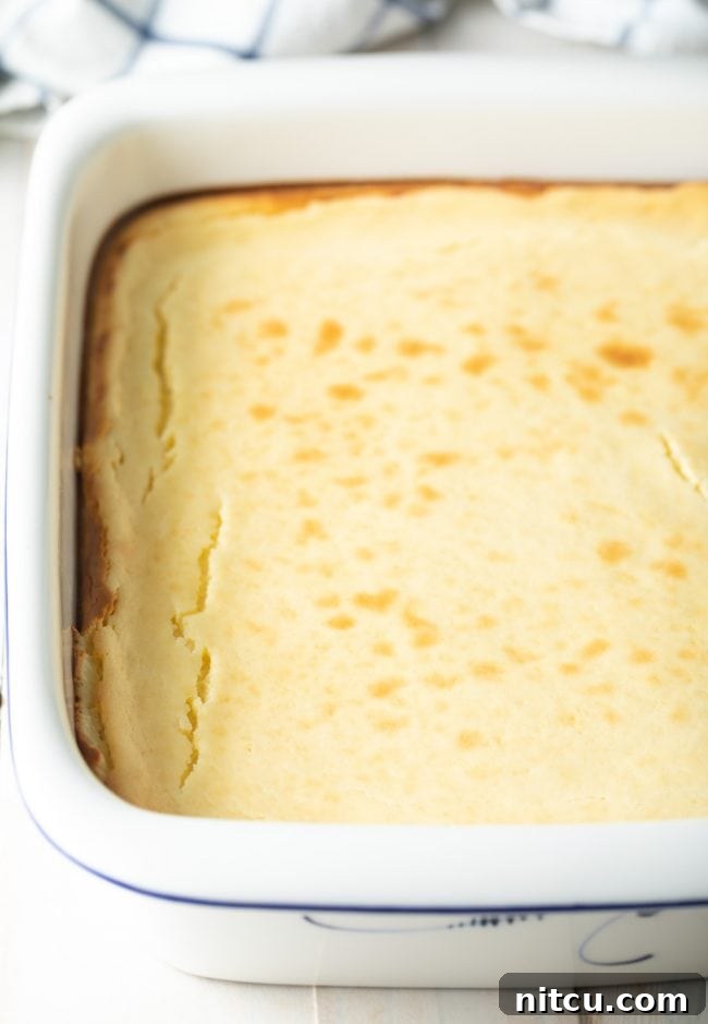 Creamy cheesecake filling poured over the crust in a square baking dish, ready for baking.