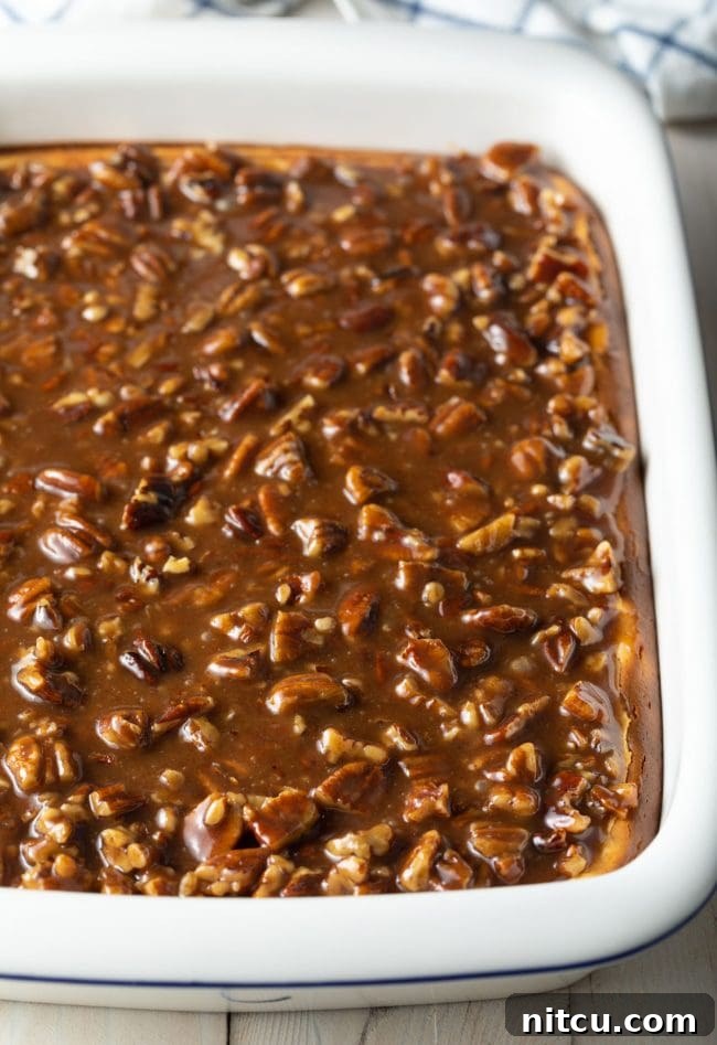 A full baking dish of Pecan Pie Cheesecake bars, showcasing the beautiful layers and ready to be sliced.
