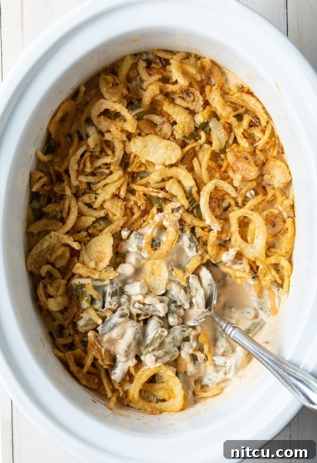 Delicious and creamy Crockpot Green Bean Casserole from scratch, topped with crispy fried onions, ready to serve for a holiday feast.
