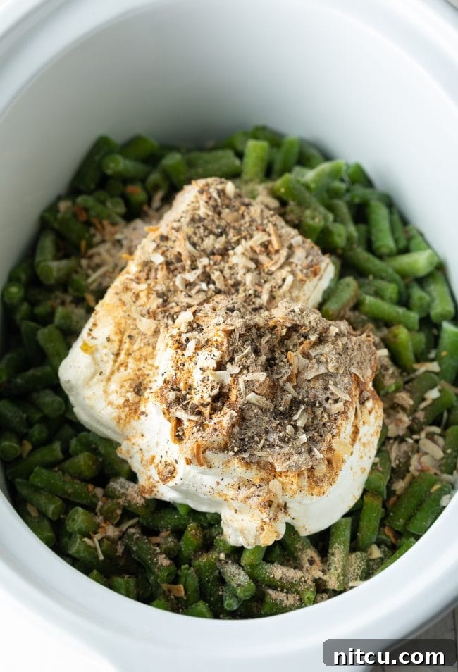A vibrant flat lay of Crockpot Green Bean Casserole ingredients: frozen green beans, softened cream cheese, onion soup mix, and sour cream.