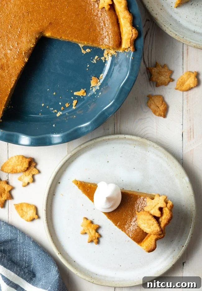 Overhead shot of pumpkin pie slice on a plate next to the rest of the pie. 