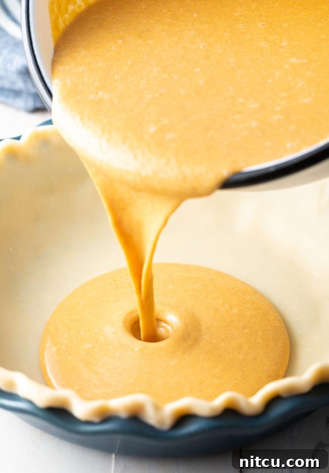 Pouring the pumpkin pie mixture into a pie crust lined pie pan. 