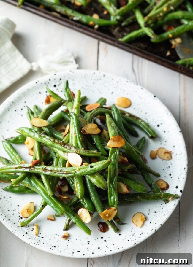 roasted green bean almondine piles on a plate
