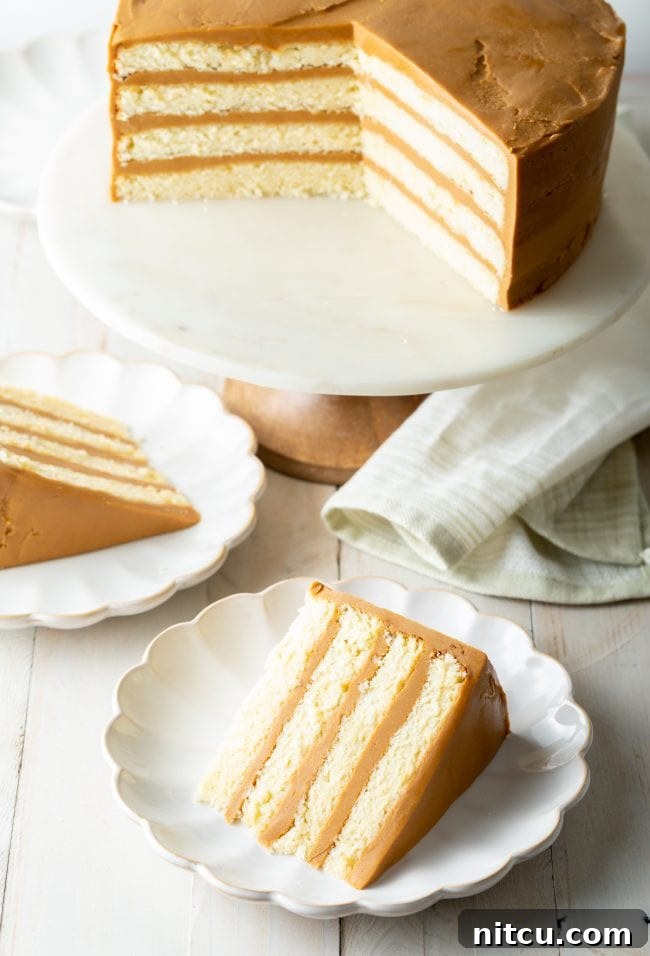 A beautifully presented Southern caramel cake, with perfect layers visible, displayed on elegant scalloped dishes, inviting a taste.