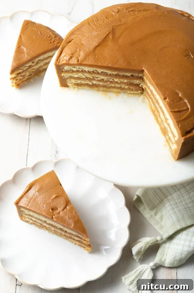 Top view of a beautifully assembled Southern caramel cake on a stand, with several slices already served on elegant scalloped dishes.
