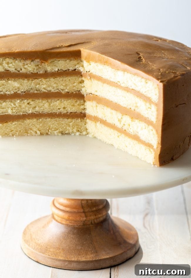 Layers of perfectly baked white cake, ready for frosting, displayed on a marble and wood stand.