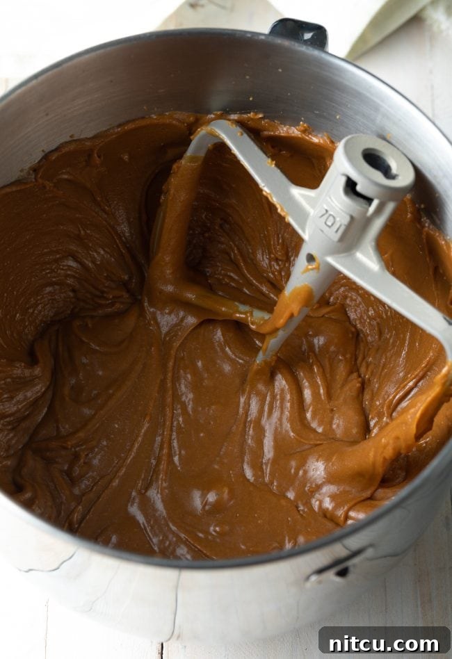 Salted caramel frosting being beaten in a stand mixer, showcasing its unique, dense yet spreadable texture.