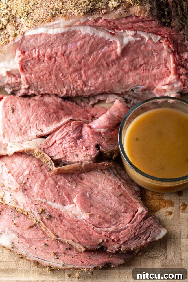 Close-up of perfectly sliced medium-rare smoked prime rib with natural au jus