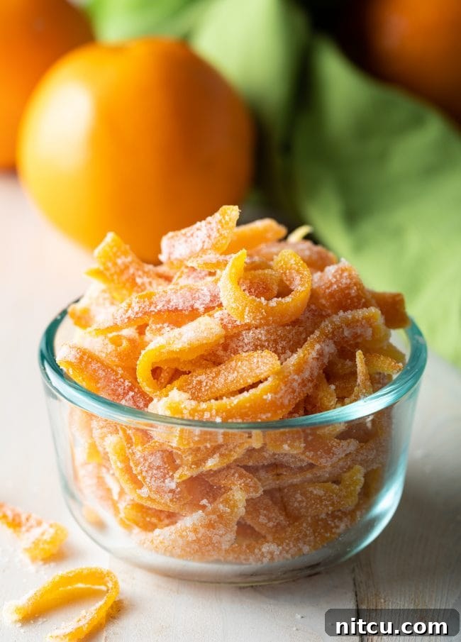 Small glass bowl filled with radiant candied orange peels, ready to be enjoyed or used as a festive garnish.