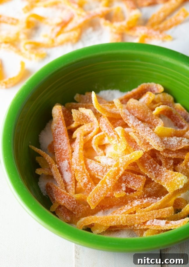 A bowl of granulated sugar ready for coating vibrant orange rinds, a crucial step in making the easiest candied orange peel.