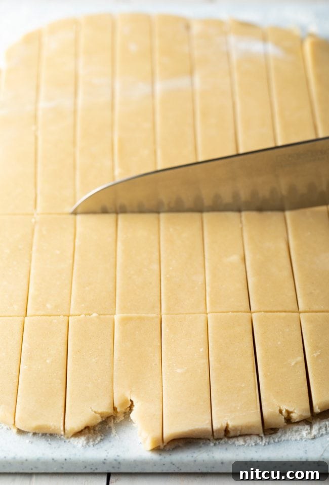 Large chef's knife slicing the dough into small rectangles. 