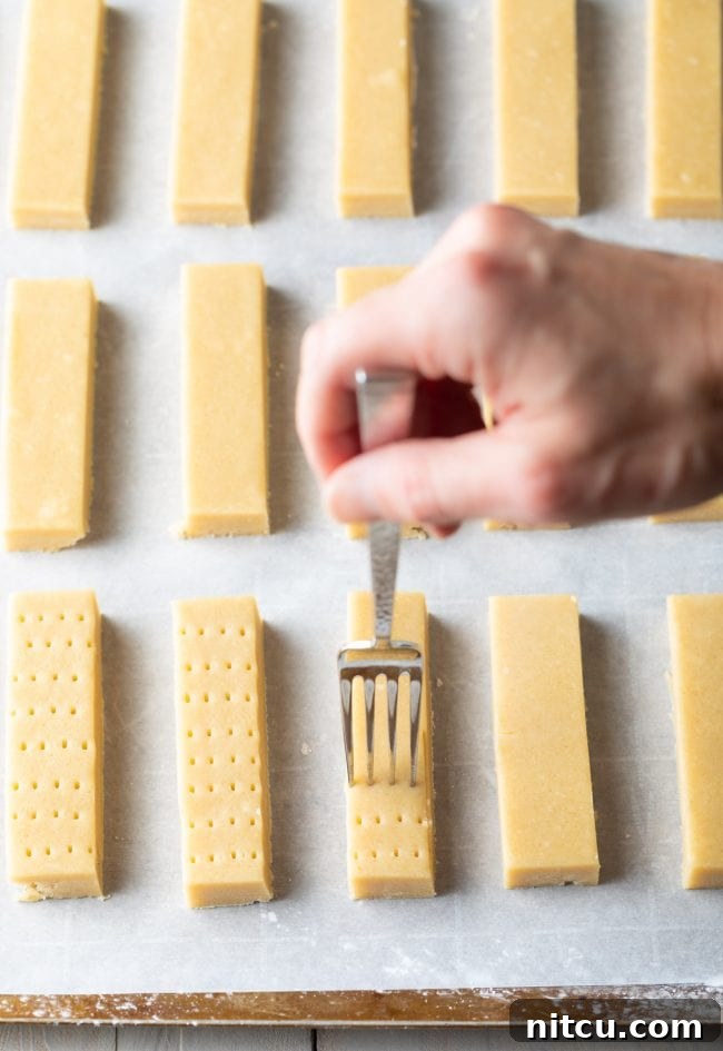 Hand poking holes in shortbread before it is baked. 