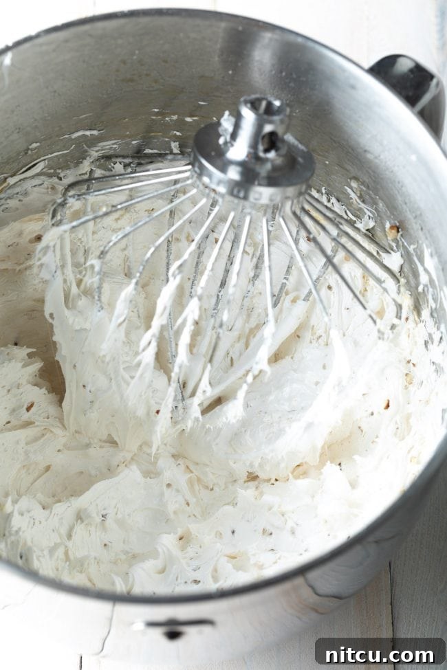 Whipped meringue for the divinity recipe in a stand mixer with the whip attachment.