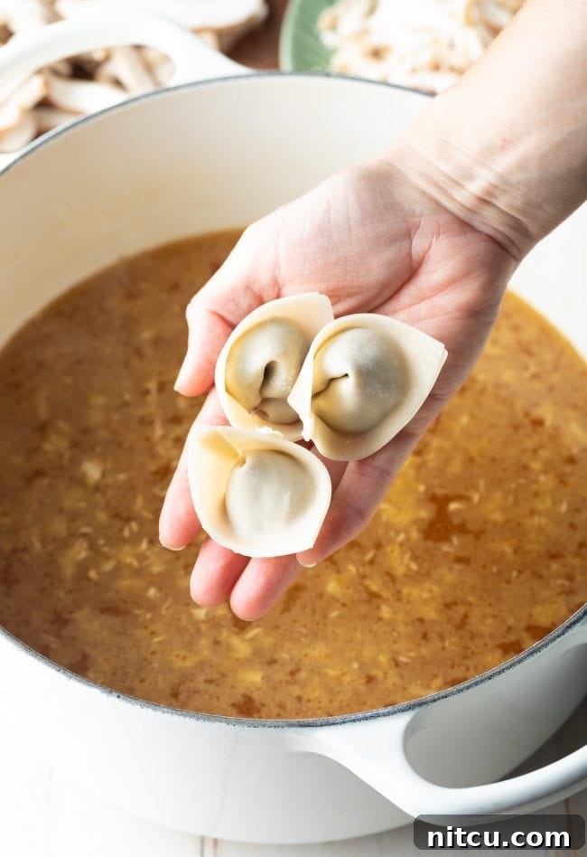 Delicate wontons being carefully added to the simmering soup base in a pot.