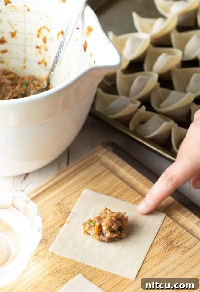 Homemade wonton filling meticulously placed on a wonton wrapper, ready for folding.