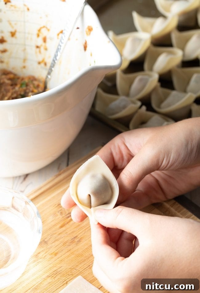A series of freshly folded wontons, perfectly shaped and ready for cooking.