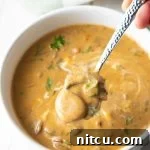 A bowl of creamy Hungarian Mushroom Soup with a swirl of sour cream and fresh dill garnish.
