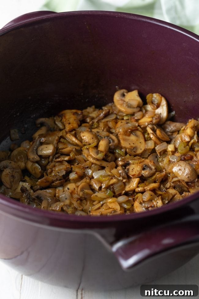 Sliced mushrooms and chopped onions sautéing in a large soup pot.