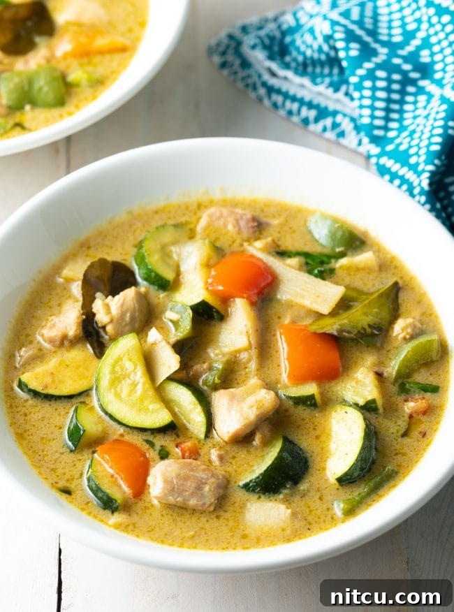 A steaming bowl of vibrant green chicken curry, perfectly plated and ready to enjoy.