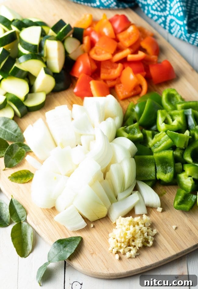 Freshly chopped bell peppers, onions, and zucchini on a cutting board, ready for the Instant Pot.