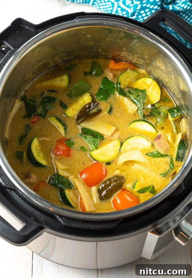 A vibrant green chicken curry bubbling gently in the Instant Pot, nearly ready to serve.