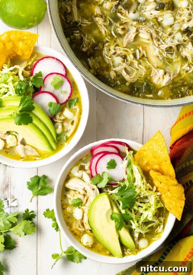 Pozole Verde de Pollo - Chicken posole served in white bowls topped with cabbage, radish, avocado and tortilla chips. 