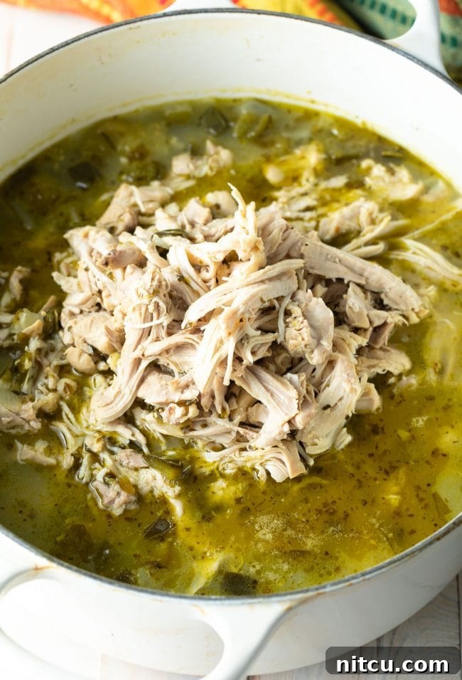 Shredded chicken being added back into the Pozole Verde pot. 