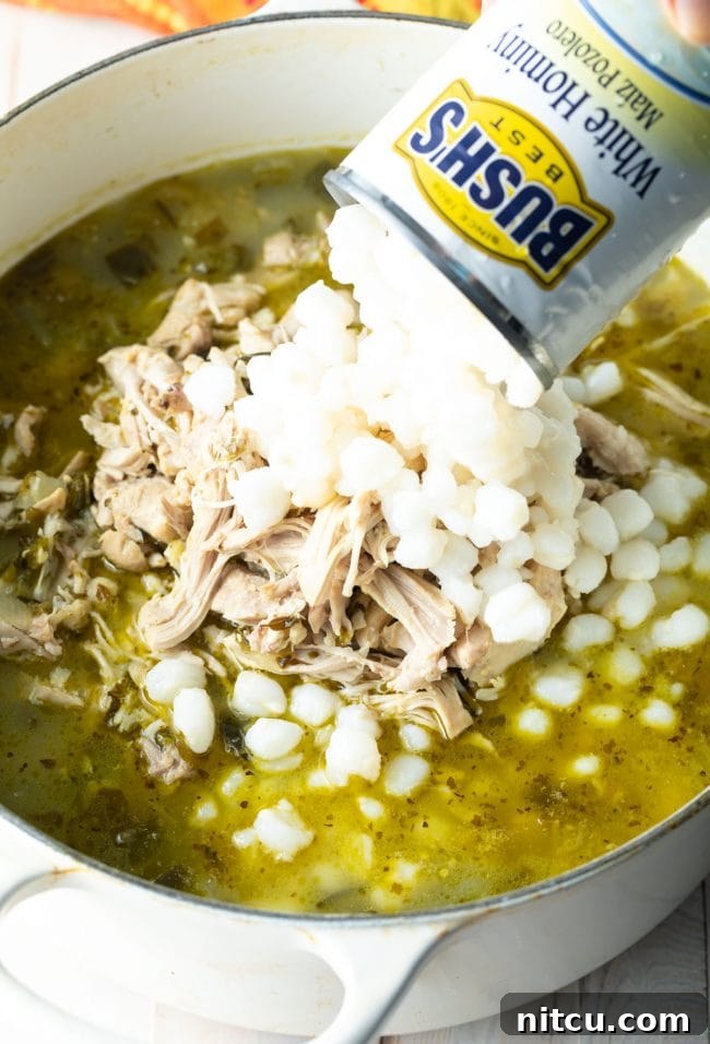 Can of white hominy being added to the pot of pozole verde. 