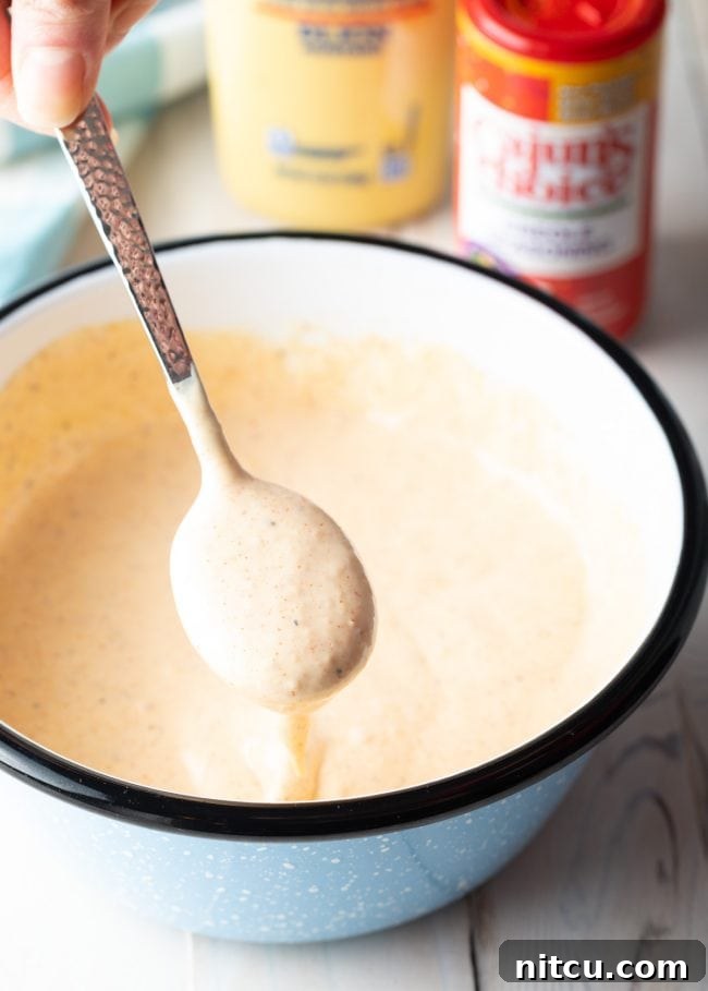 Spoon scooping up some of the remoulade sauce from a mixing bowl.