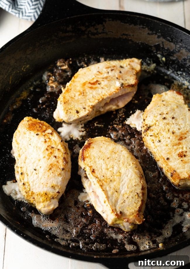 top view of pan seared pork chops in a cast iron skillet golden
