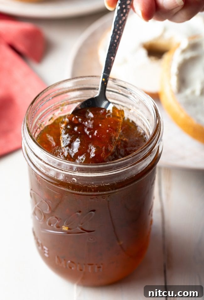 Hot pepper jelly recipe being spooned out of a jar. Creamy texture.
