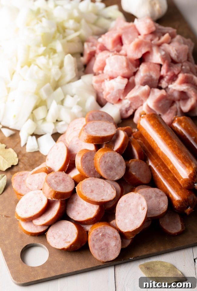Chopped onions, ham and sausages on a cutting board.