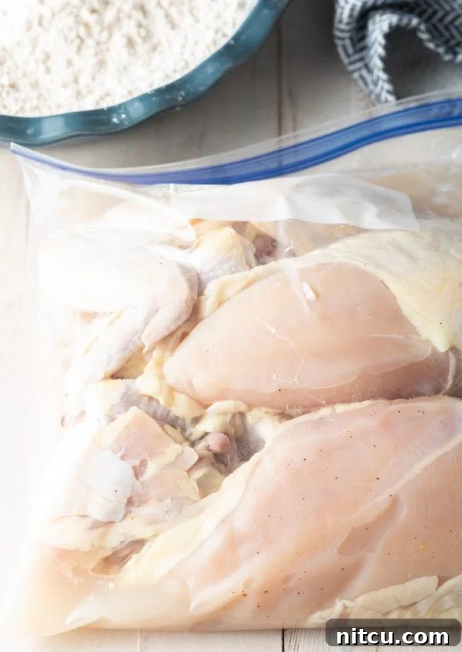 Chicken pieces marinating in a clear zip-top bag with a pickle juice brine, ready for flavoring.