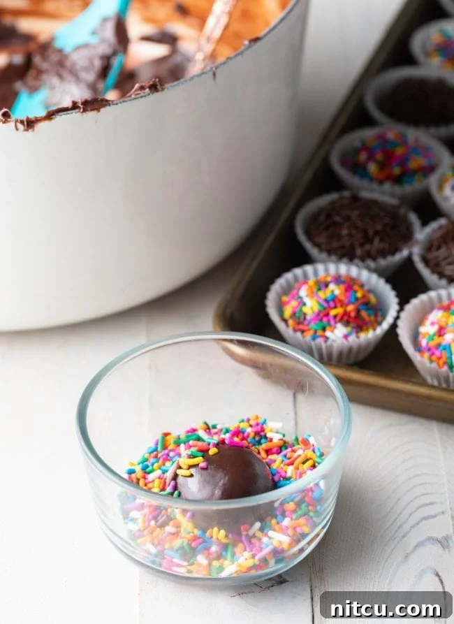 A shot of Brazilian truffle fudge balls being coated in sprinkles, showing the hands gently rolling the truffles in the colorful toppings.