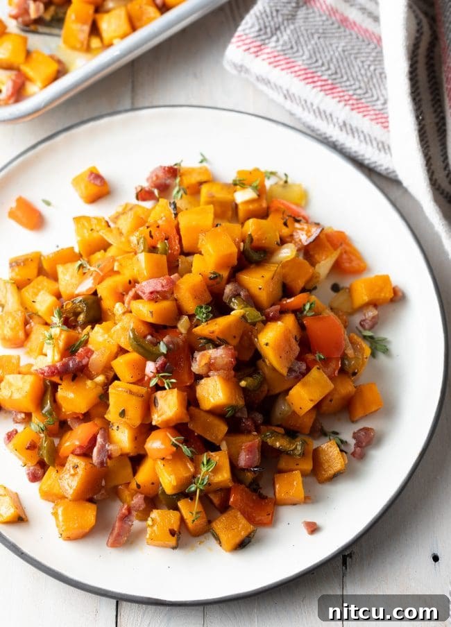 A top-down view of a white plate generously filled with golden-brown sweet potato hash, artfully arranged for serving.
