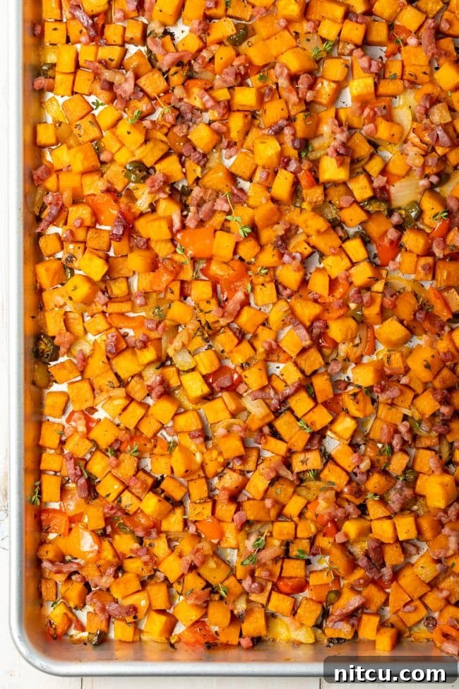 An overhead shot showcasing perfectly cooked sweet potato hash browns spread across a baking sheet, featuring crispy edges and vibrant colors.
