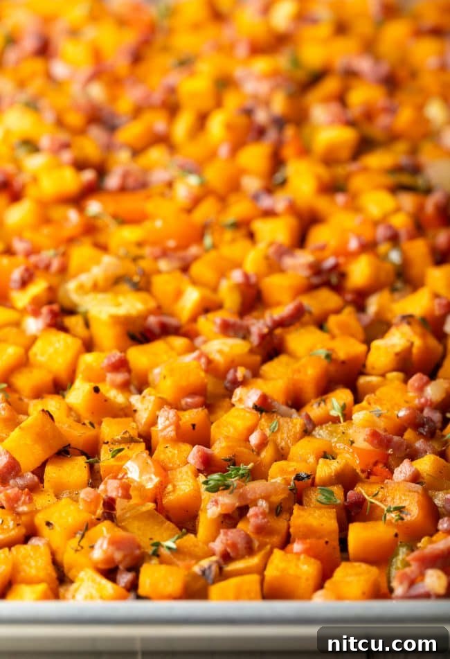A close-up view of golden-brown sweet potato hash browns on a baking sheet, showcasing their crispy texture and the colorful mix of ingredients.