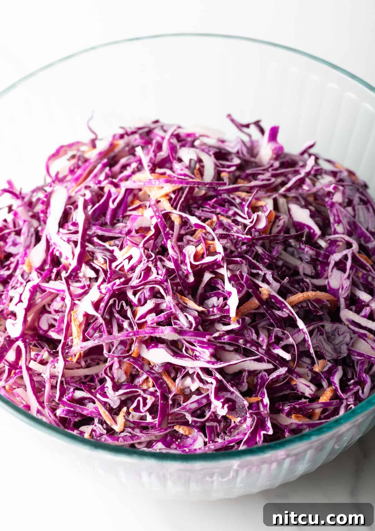 Overhead shot of a red cabbage slaw recipe in a glass bowl.