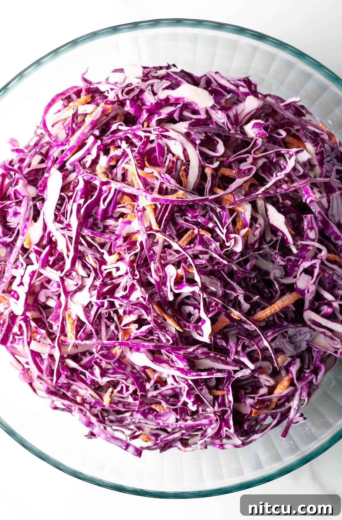 Overhead shot of a red cabbage slaw recipe in a glass bowl.