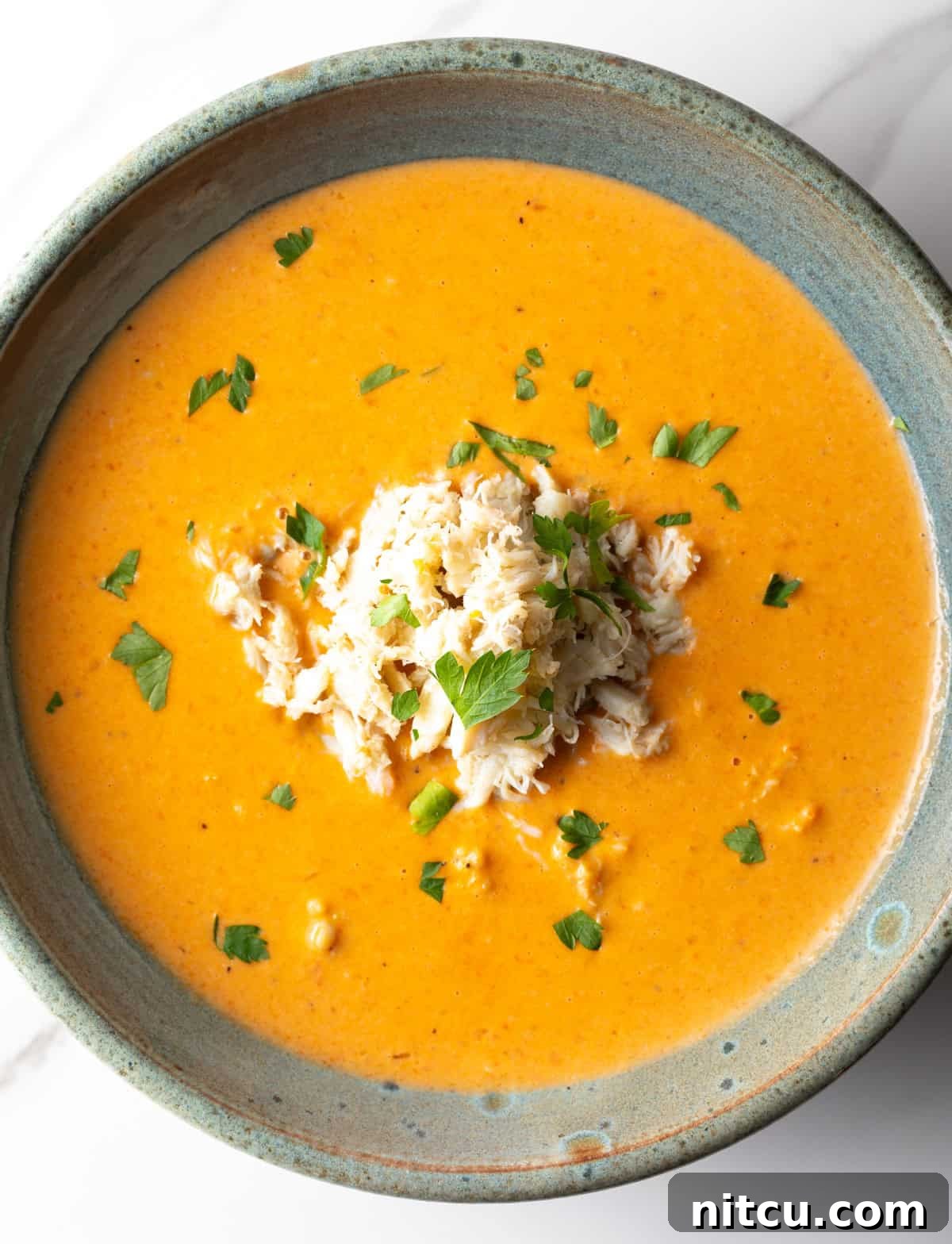 An overhead shot of a crab bisque recipe in a grey bowl.