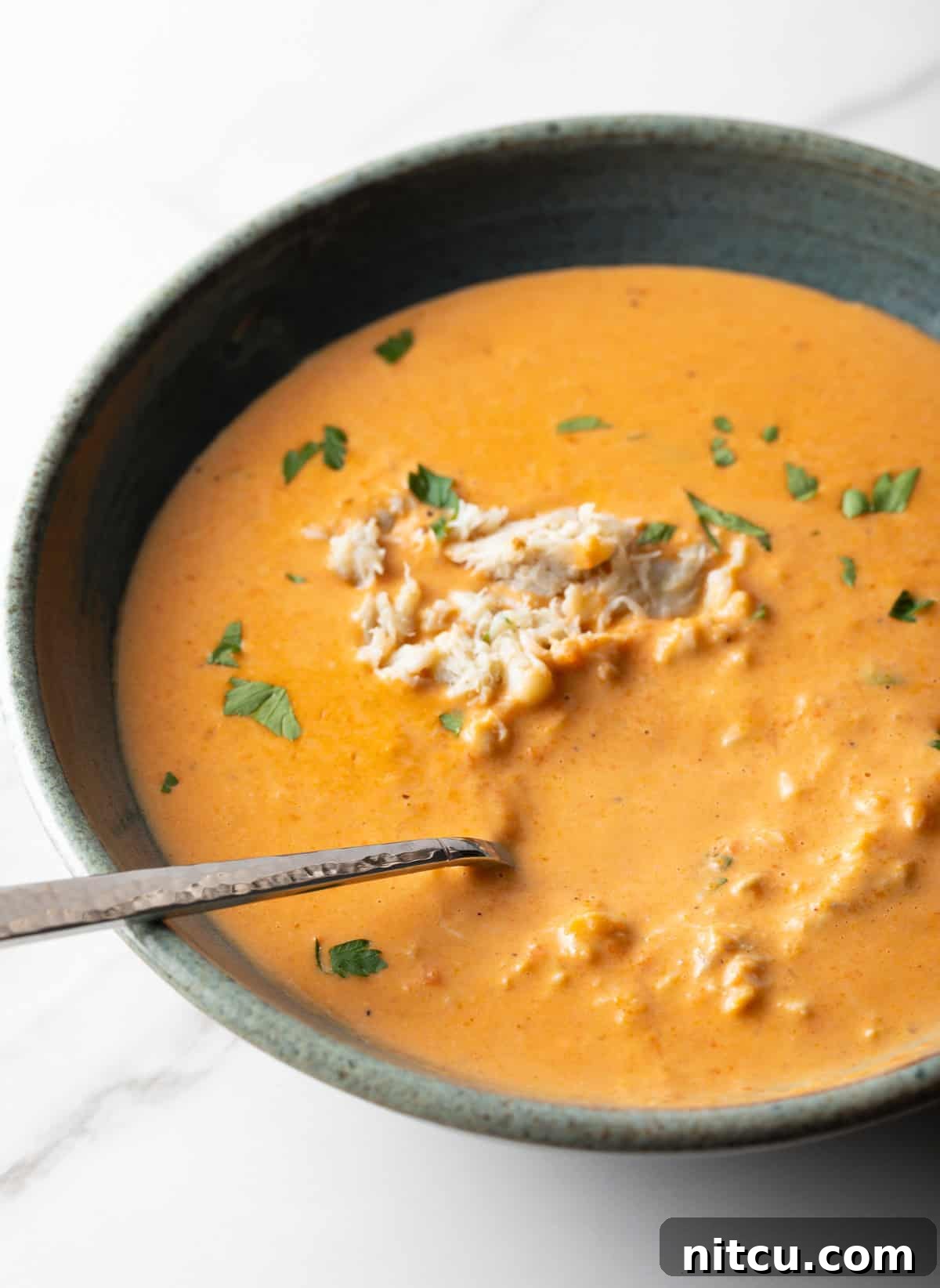 A bowl of easy crab bisque soup with a metal spoon in the bowl.