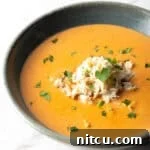 A black bowl filled with creamy crab bisque soup with crab meat and parsley on top.