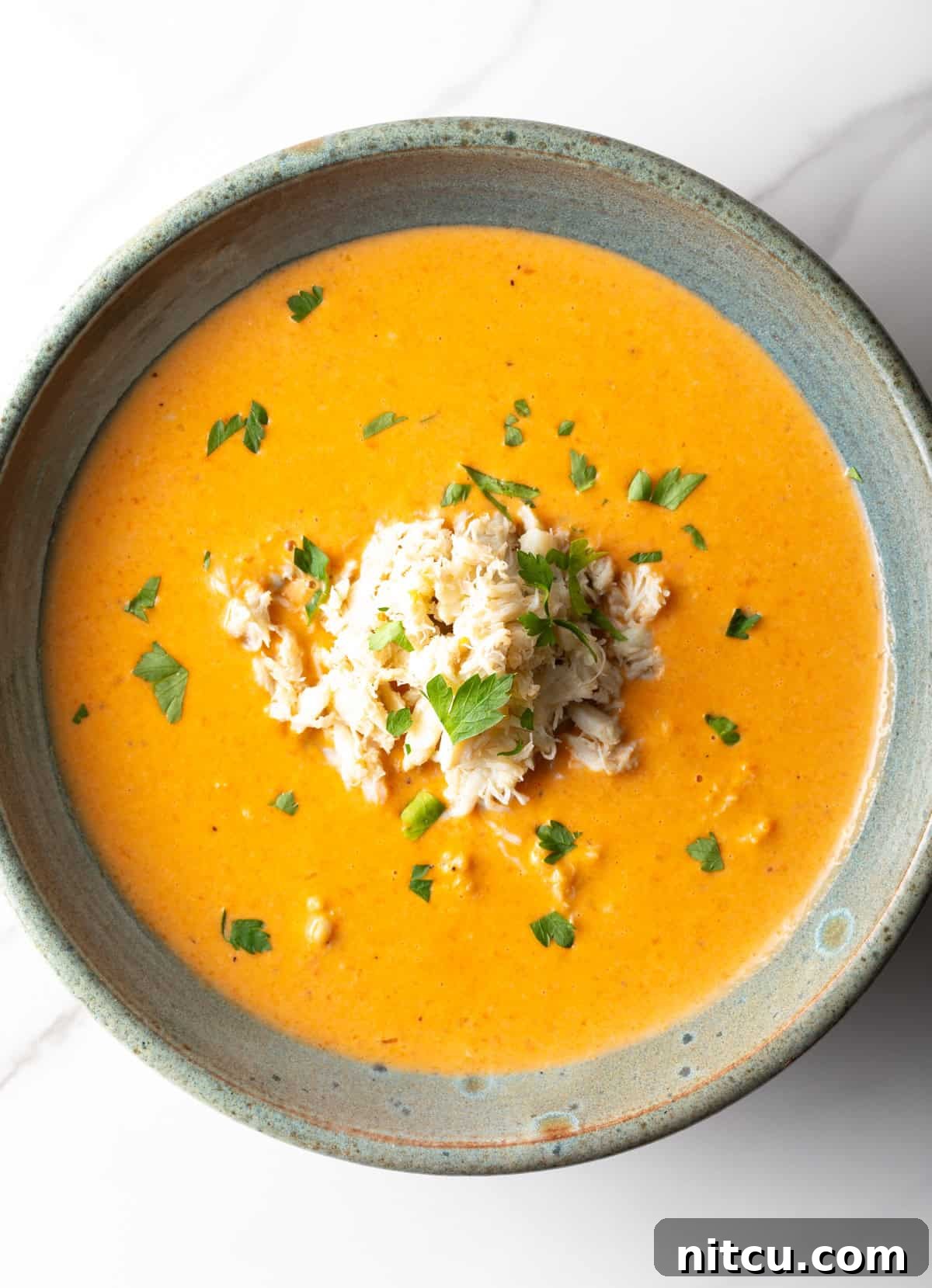An overhead shot of a crab bisque recipe in a black bowl.