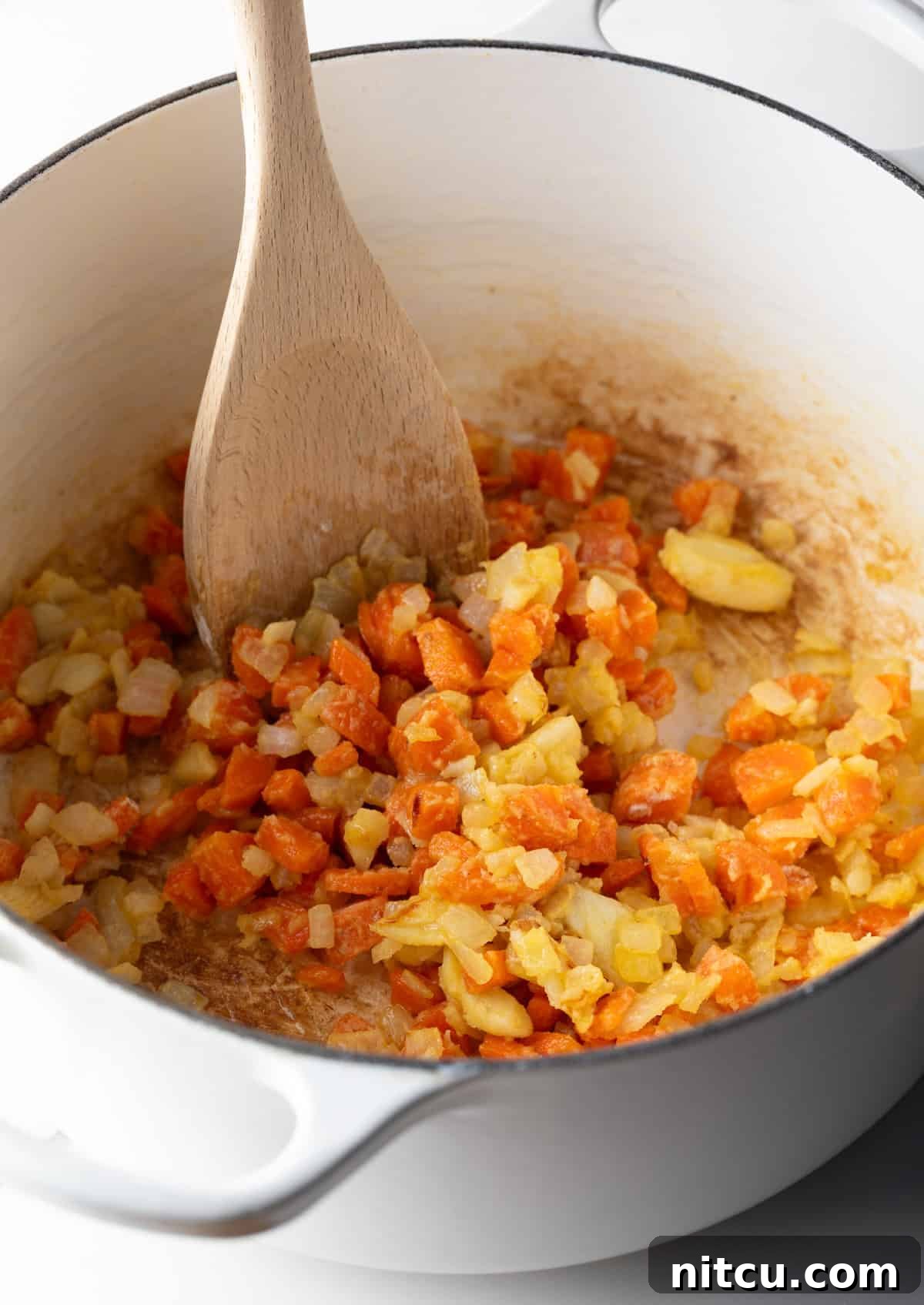 Flour is being stirred into the sautéed veggie mixture.