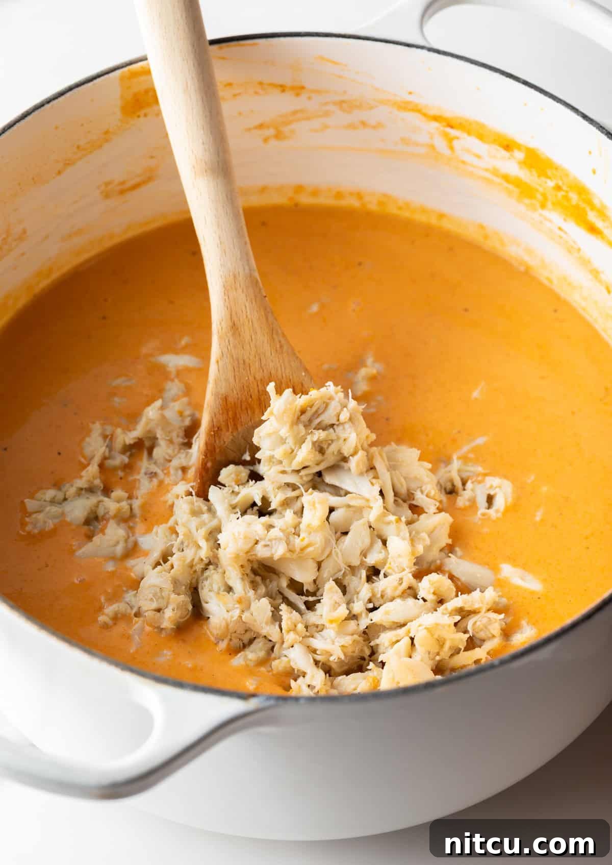 Crab meat is being added to a crab bisque soup recipe.